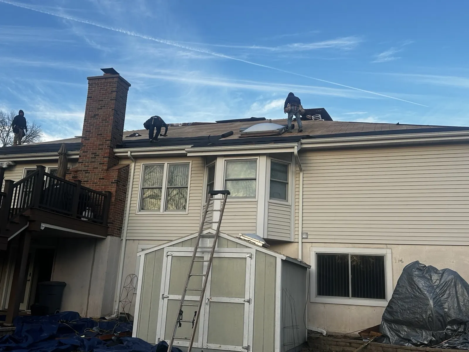 Nextdoor crew installing shingles on the back of the house